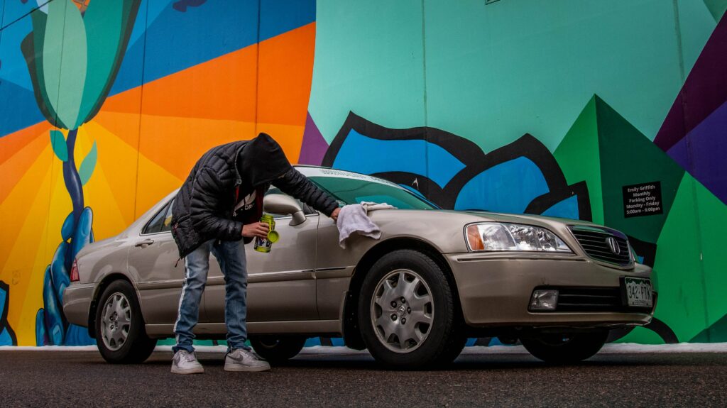 Mann putzt Auto mit Lappen