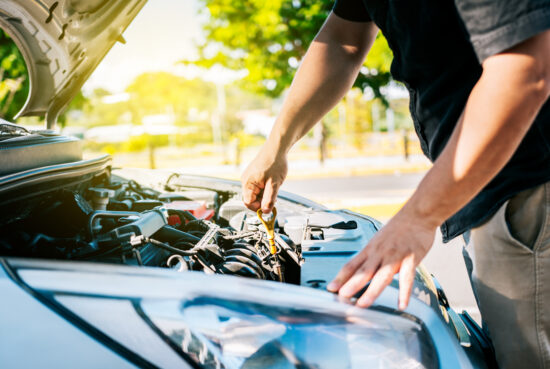 Driver hand inspecting car oil level. Man hand checking oil to car with copy space. People hand inspecting car oil level Motorölcheck